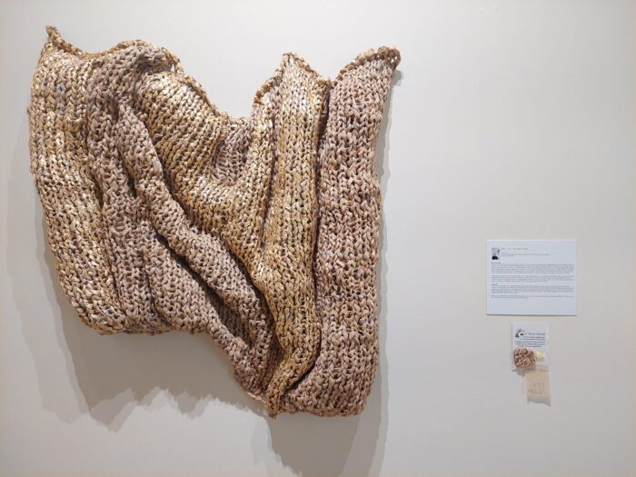 Wallmounted sculpture of factory waste dressmakers' pattern tissue, gold foil and aluminum wire, with a tactile sample beside it